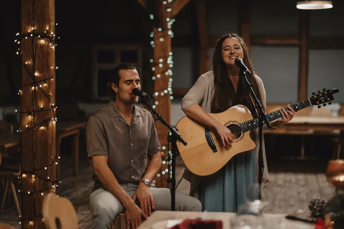 Sunny und Marty singen bei einer Hochzeitsfeier in einer festlich beleuchteten Scheune